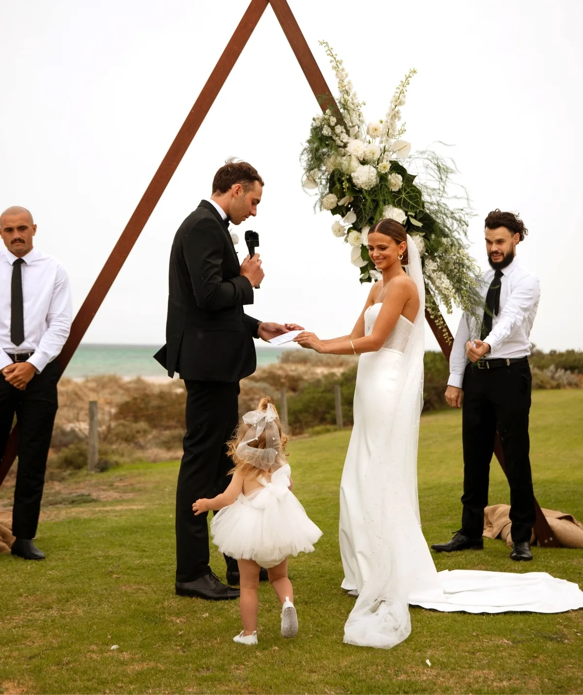 Kellie, Jeremy and Sophia stand in a field on their wedding day.