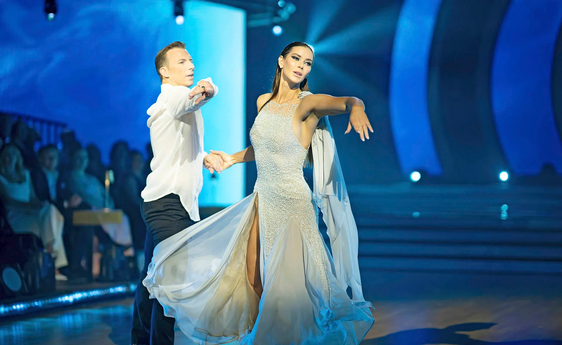 Brittany Hockley and her dance partner Craig Monley, dressed in white, do the waltz on the dance floor.