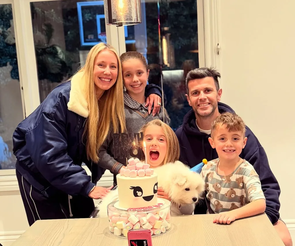 Trent, his wife Brooke and their three children pose behind a birthday cake.