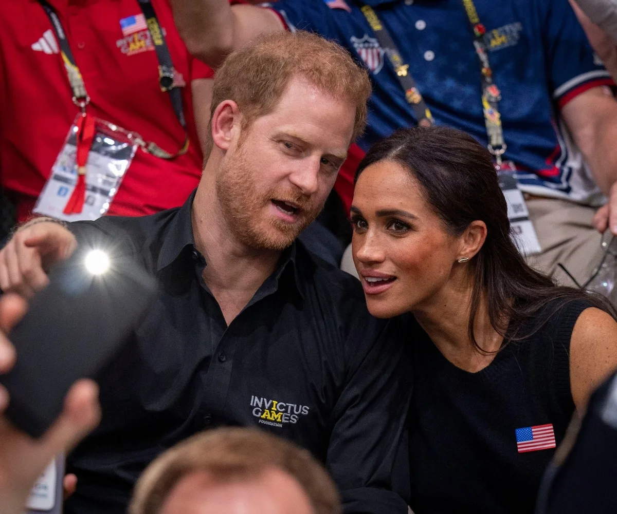 Harry and Meghan lean into one another in the crowd at a game.