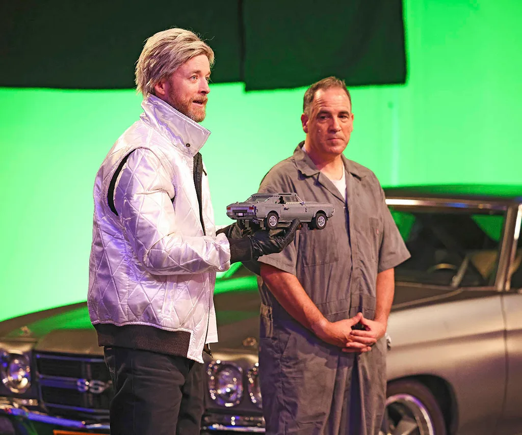 Hamish and Brickman dressed as characters from Back to the Future in front of a black car and green background.