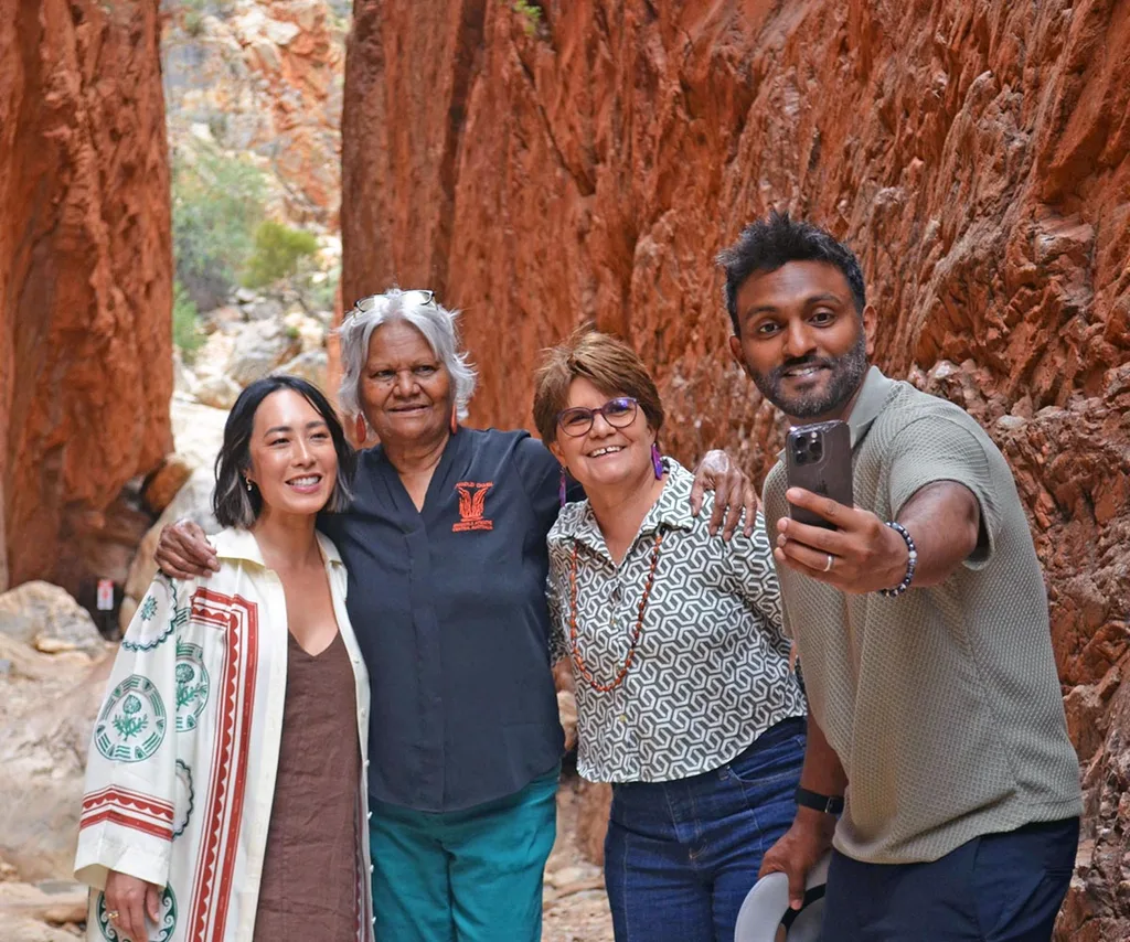 Mel and Naz pose at Standley Chasm, with Aunty Colleen Mack and Rayleen Brown. Naz is taking a selfie of the group.