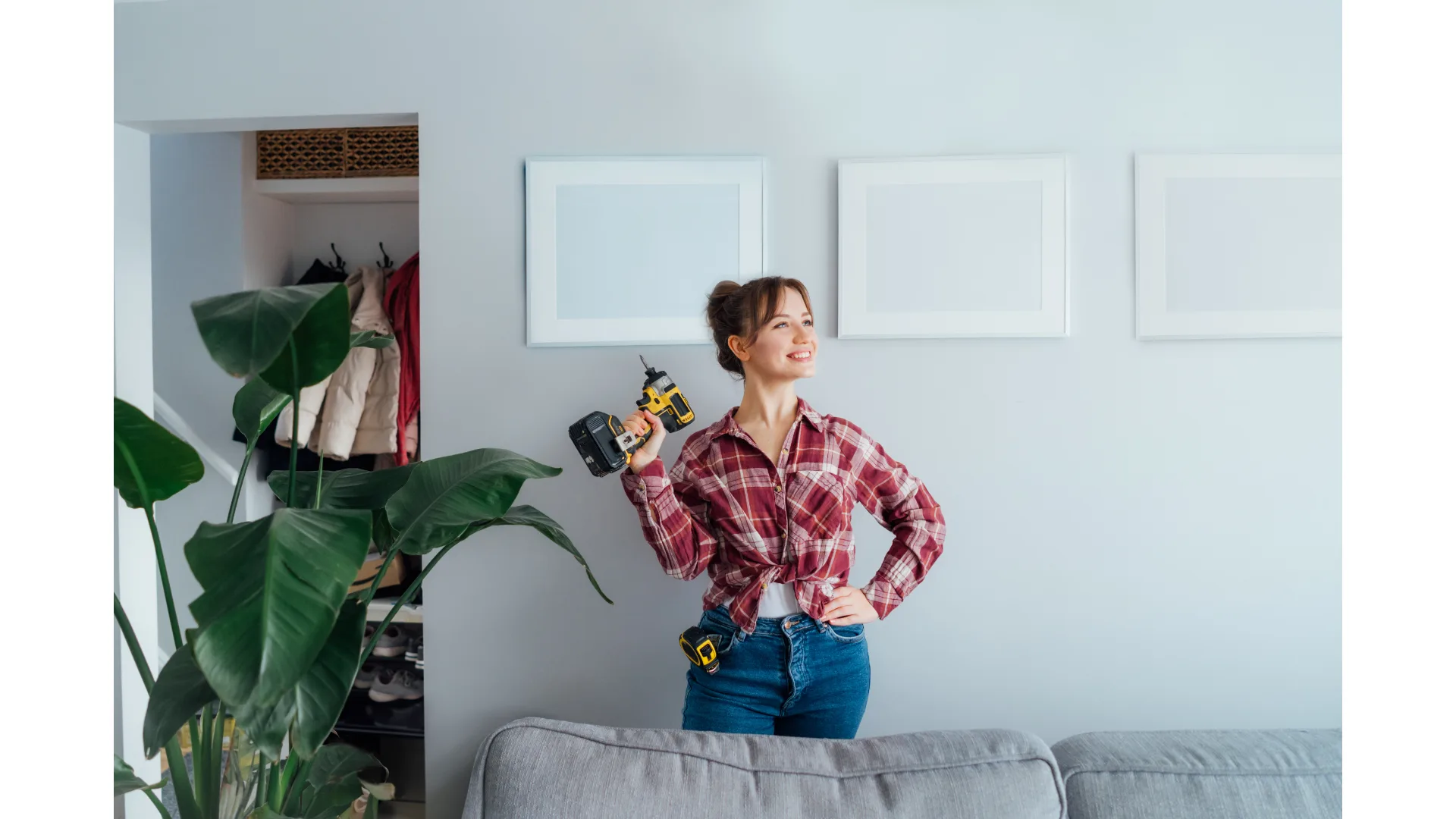 A woman dressed in a flannel shirt looks proud of herself as she holds a power drill.