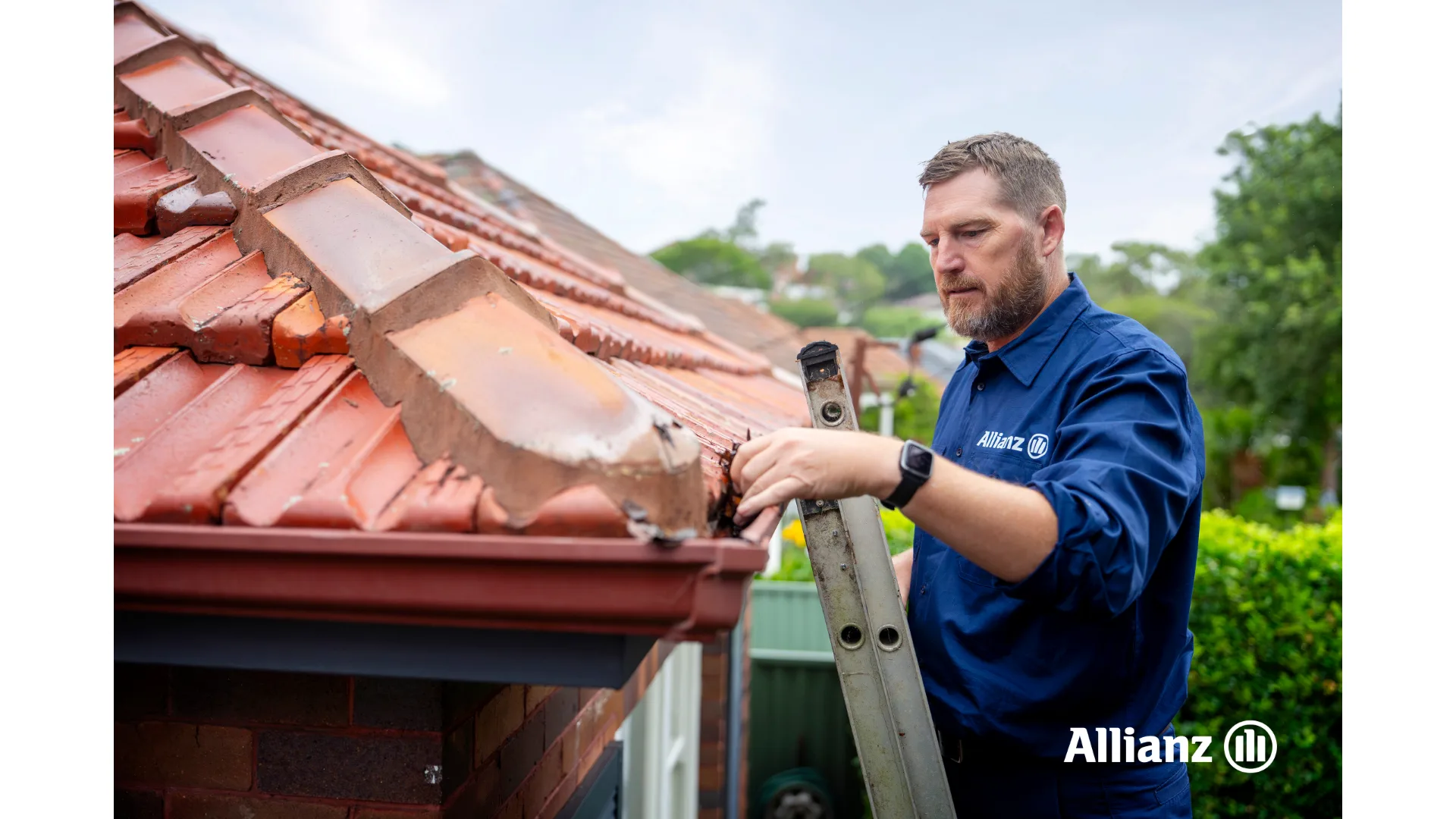 A man in an Allianz shirt cleans out a home's awning.