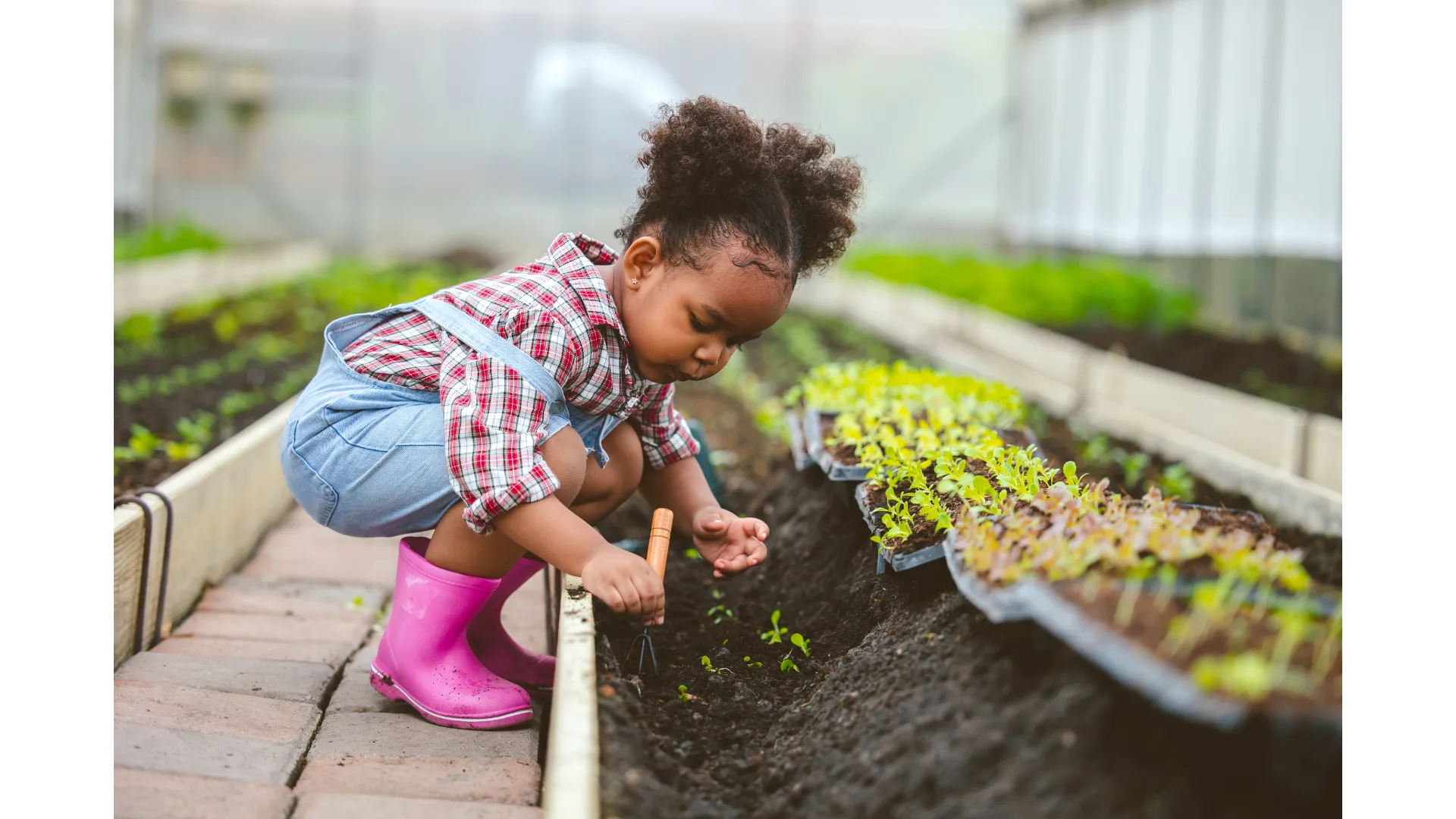 A young girl plays in the soil while helping in the garden.