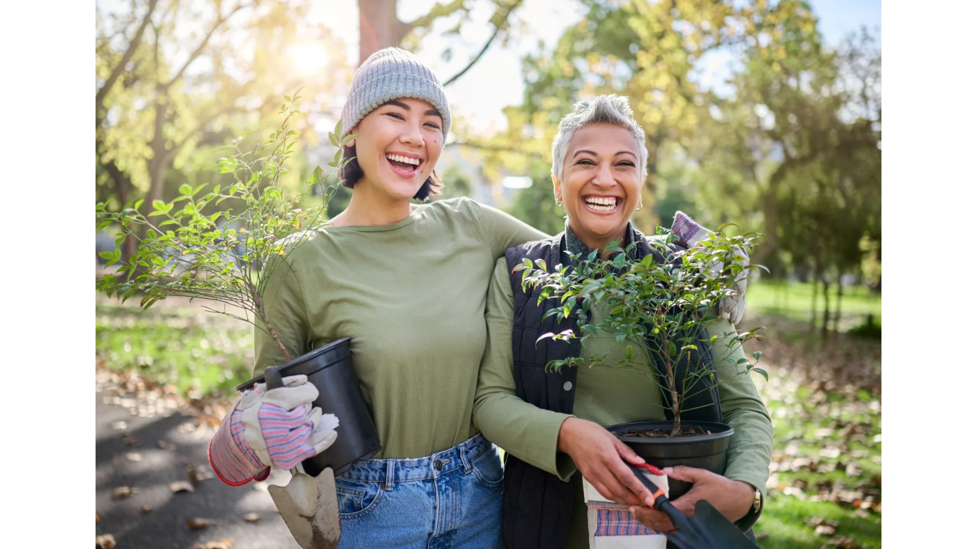 Two women embrace and share a laugh while gardening.