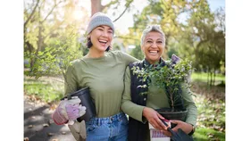 Two women embrace and share a laugh while gardening.