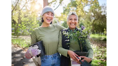 Two women embrace and share a laugh while gardening.