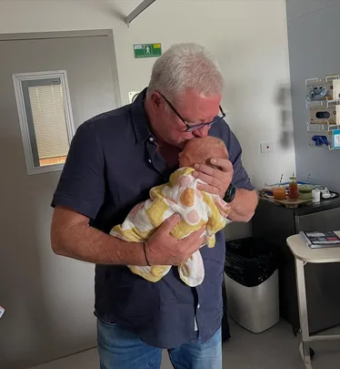 Scott Cam host of The Block kisses his granddaughter Tiggy in a hospital room.