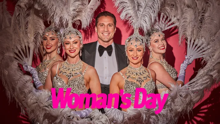 A man surrounded by women dressed as showgirls