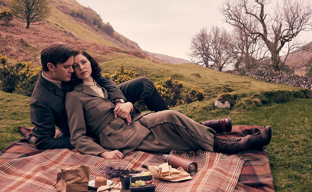 Jeremy and Hermione, as their Blood Of My Blood characters, lie next to each other on a picnic rug.