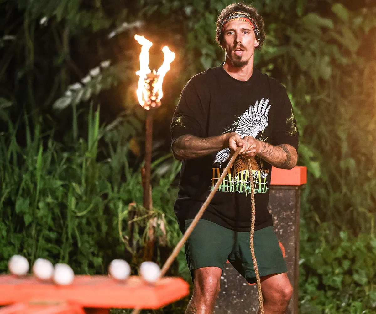 Luke, wearing a black t-shirt, focuses intently on a rope he is holding.