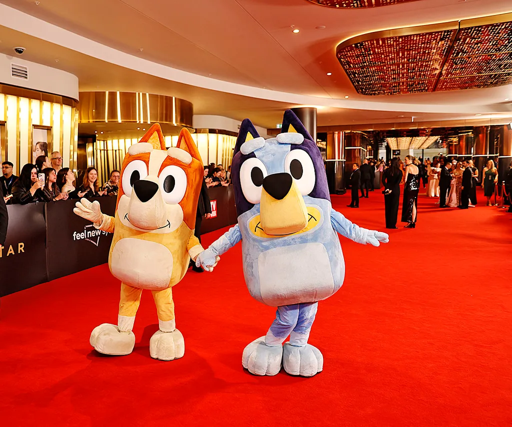 Two people dressed as Bluey and Bingo pose on the red carpet.