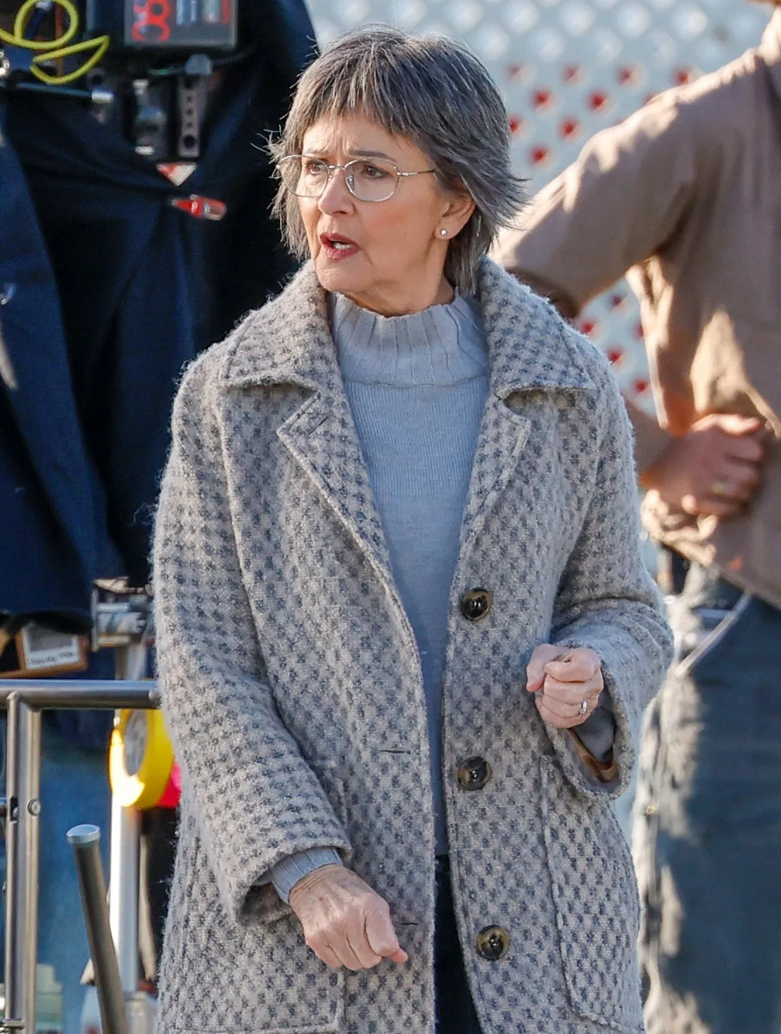 Jackie Woodburne, wearing a long coat, is in character on the set of Imposter