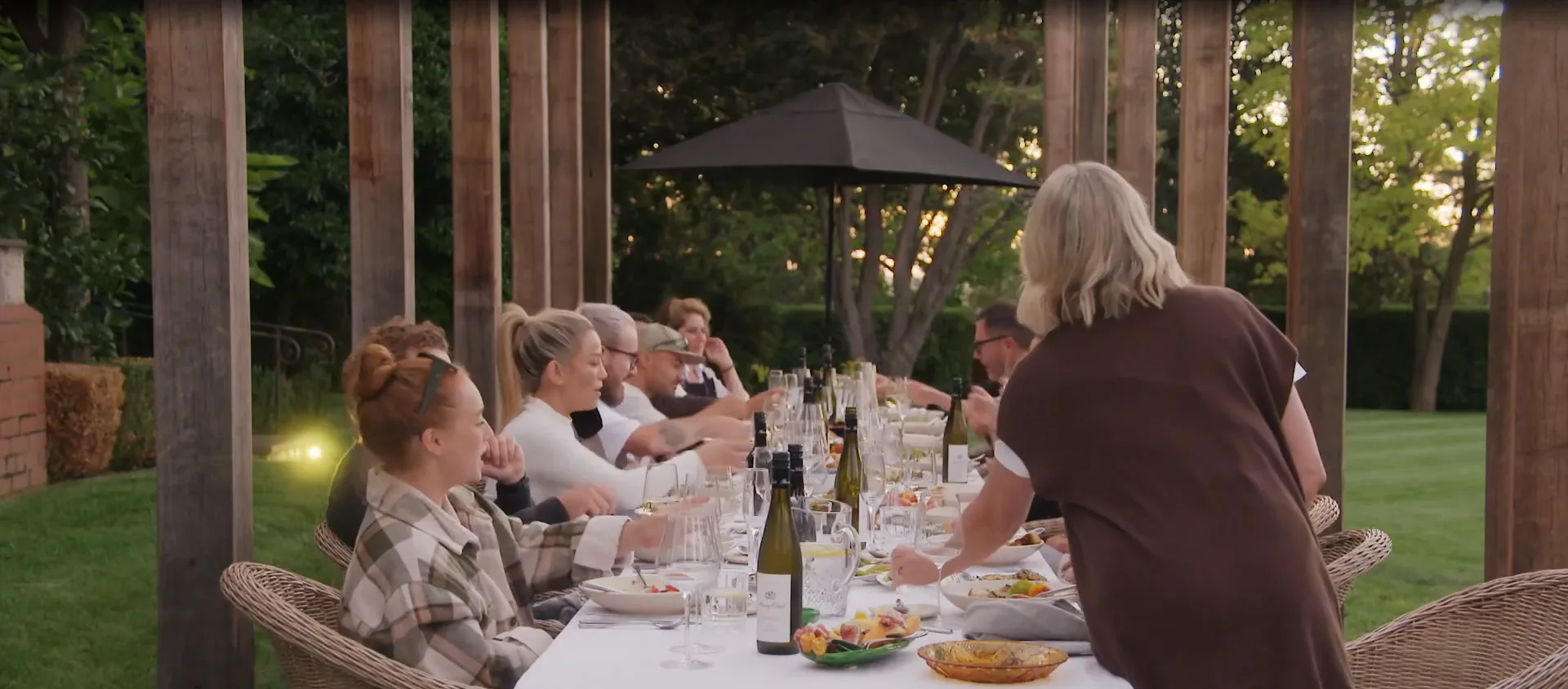 Shelley and The Block crew at a challenge in Daylesford for the 2025 series sitting at a table being told the exciting news Scott is becoming a Grandpa!