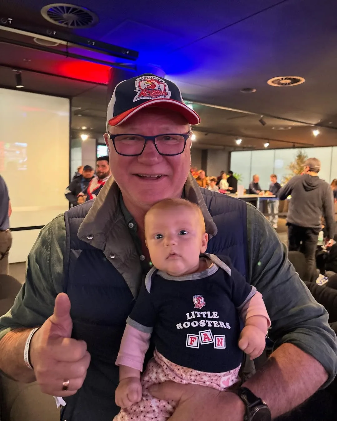 Scott Cam, host of The Block, posing happily with granddaughter Tiggy at a footy game.