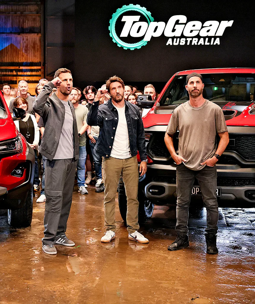 Jonathan stands on the set of Top Gear, with the other hosts of the show, and a car behind them.