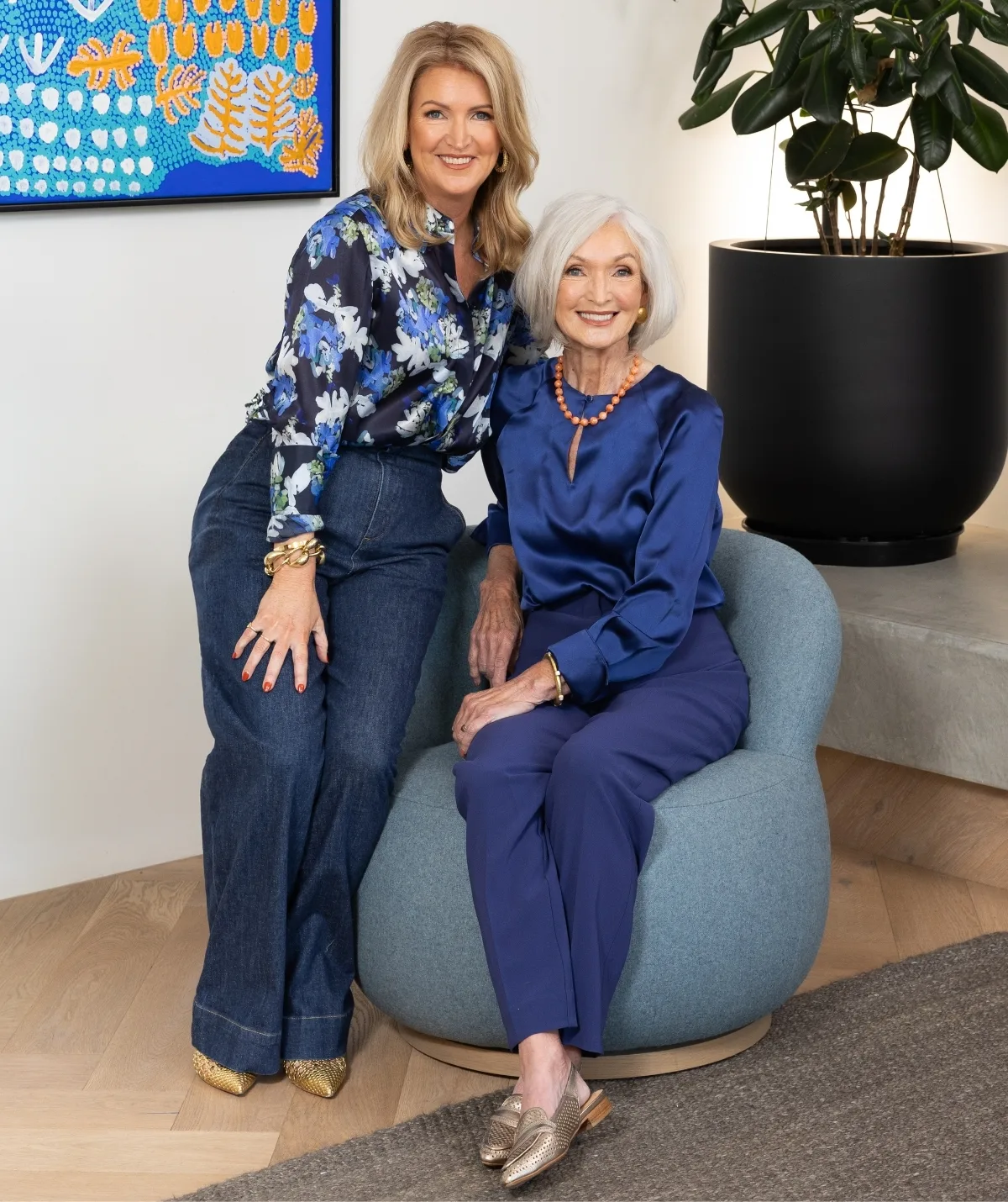 Two women sit smiling to camera