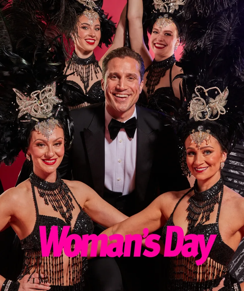 A man in a tuxedo surrounded by women in showgirl outfits