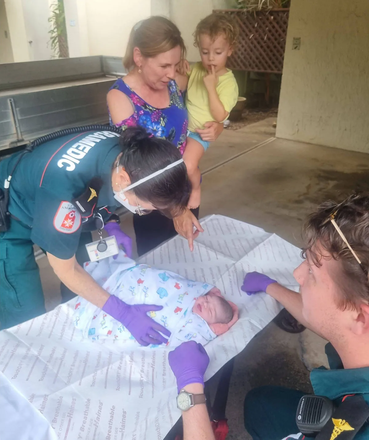 My mum Tracy with my son James and Dawn after she was born, with paramedics getting ready to take her in the ambulance. (Image: Supplied)
