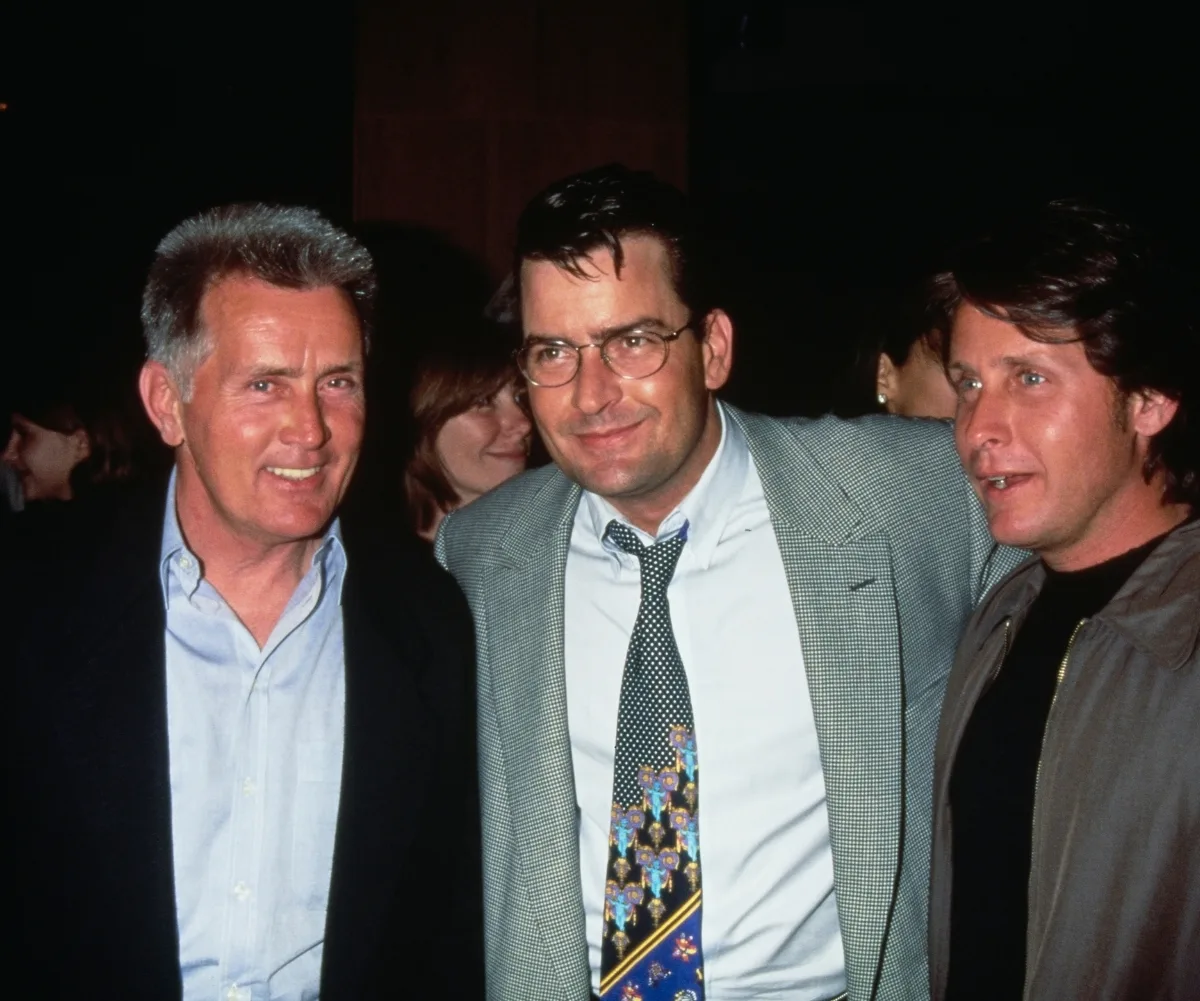 Three men with the middle one's arms around the others