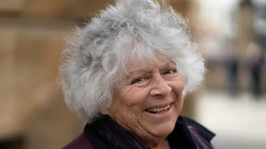 A woman with grey white hair smiling.