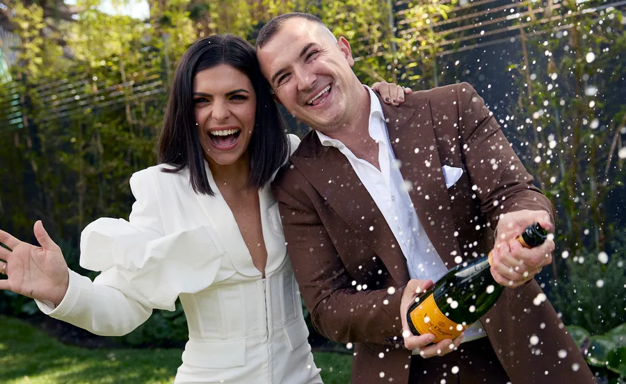 Steph and Gian winners of the 2023 series of The Block celebrating by spraying a bottle of Veuve.