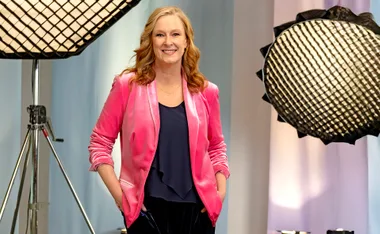 Leigh Sales, wearing a pink jacket, stands with her hands in her pockets,