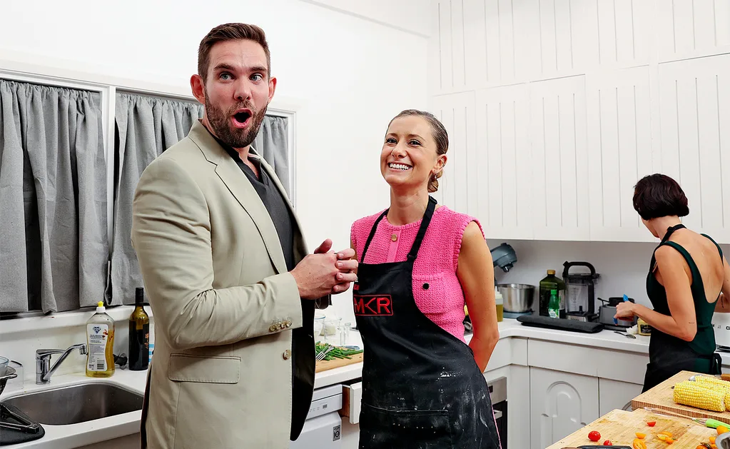 Michael stands in Mel and Jacinta's kitchen, with a shocked look on his face, while Mel smiles at him