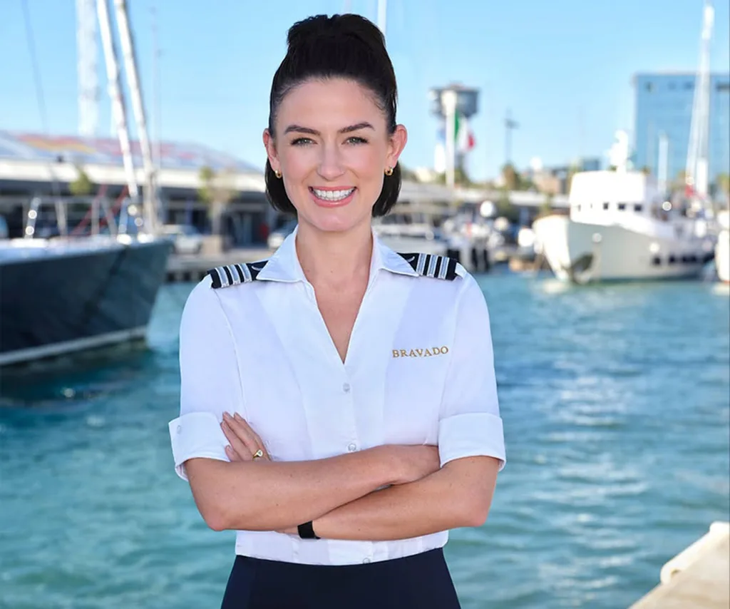 Aesha Scott in her chief steward uniform with the ocean behind her in a promotional shot for Below Deck.