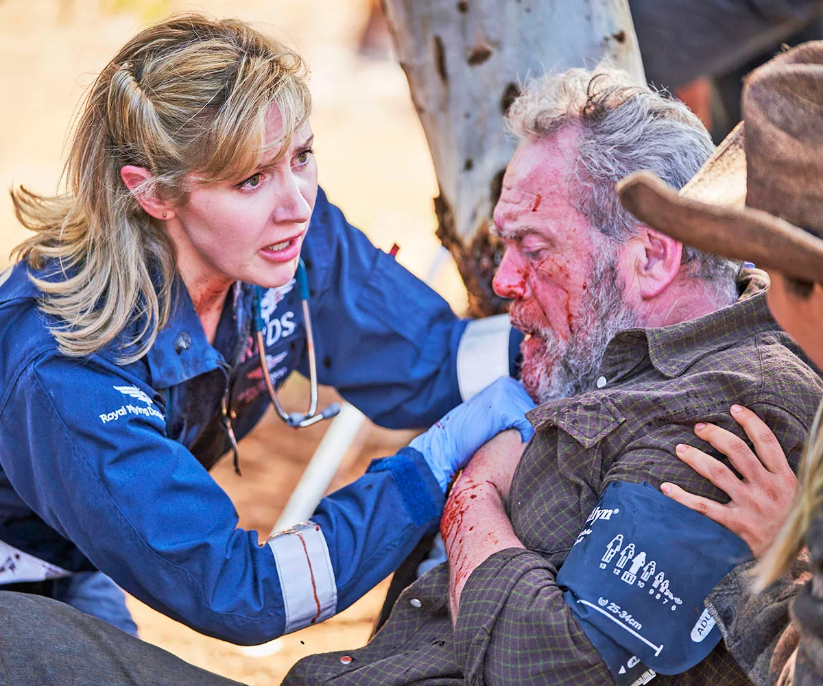 Emma Hamilton, as Eliza, looks with concern at an injured man on the set of RFDS