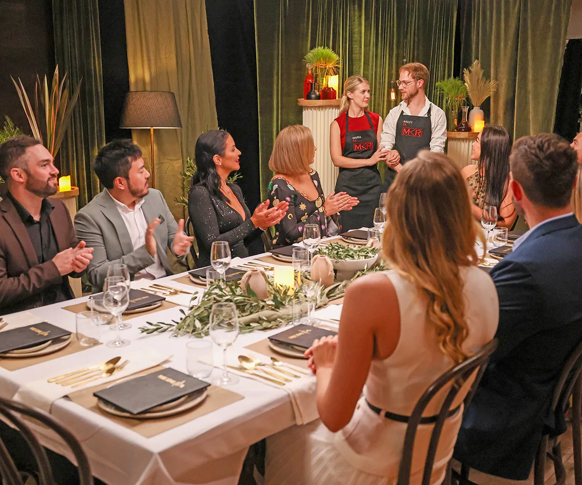 Bailey and Maria stand near the table at their instant restaurant