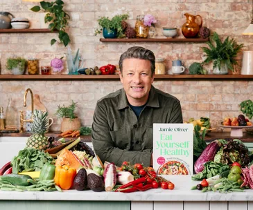 A smiling man surrounded by vegetables.