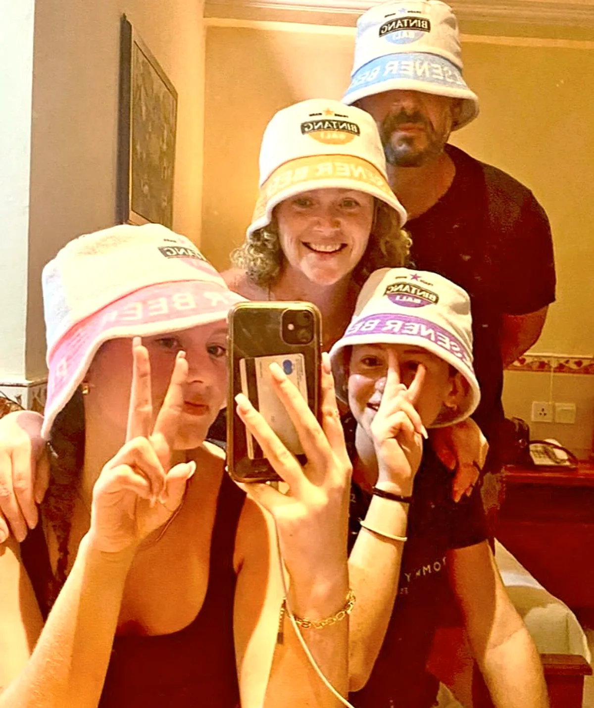 Colin Fassnidge with his wife and kids all posing in bucket hats for a mirror selfie.