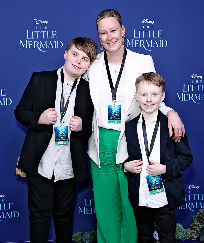 Leigh stands in the middle of her two sons, her arms around them, at a premiere
