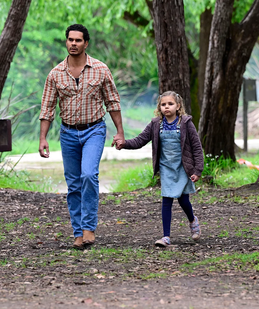 Mark holds the hand of actress Eloise Hart as they walk through some trees on the set of Mystery Road: Origin