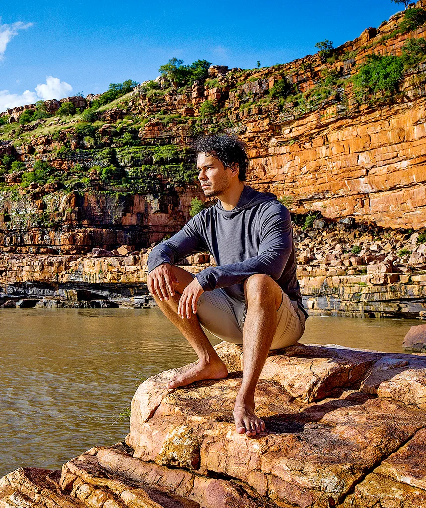 Mark sits on a rock, staring into a distance, in the Kimberley