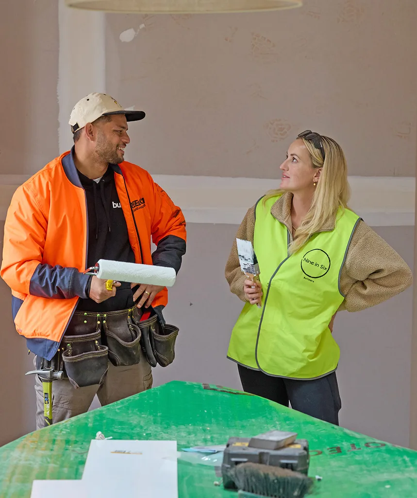 Taz and Britt on site of The Block. Taz holds a roller paint brush.