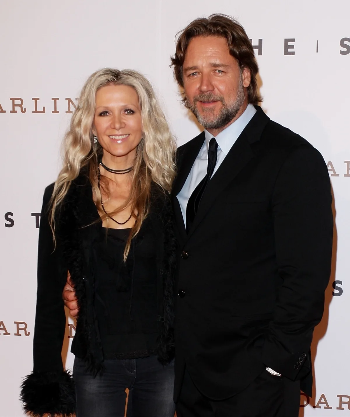 A man and a woman posing in smart dark clothes.