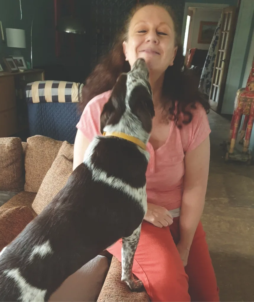 A woman is being licked by a dog.