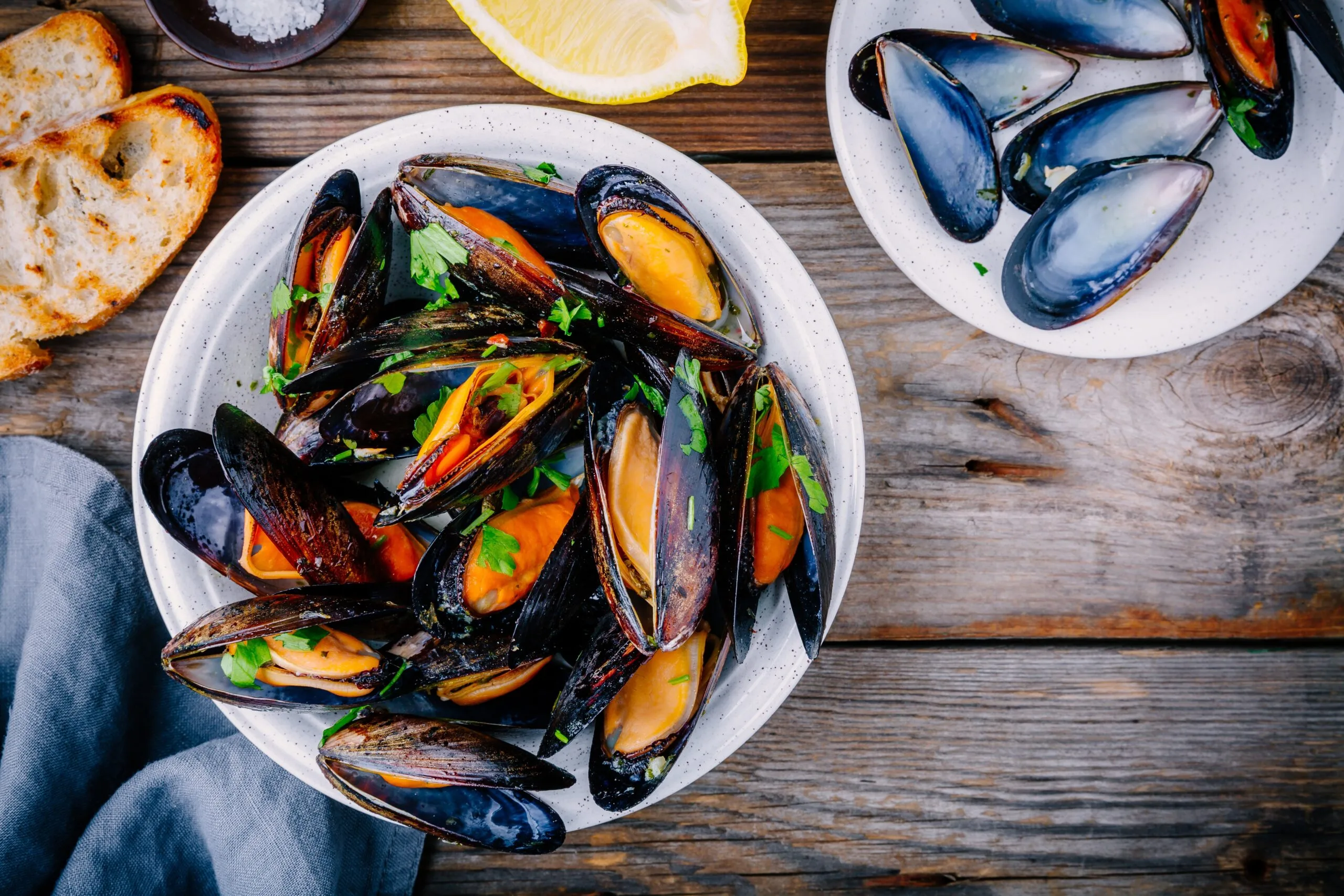 A bowl of mussels sits on a table.