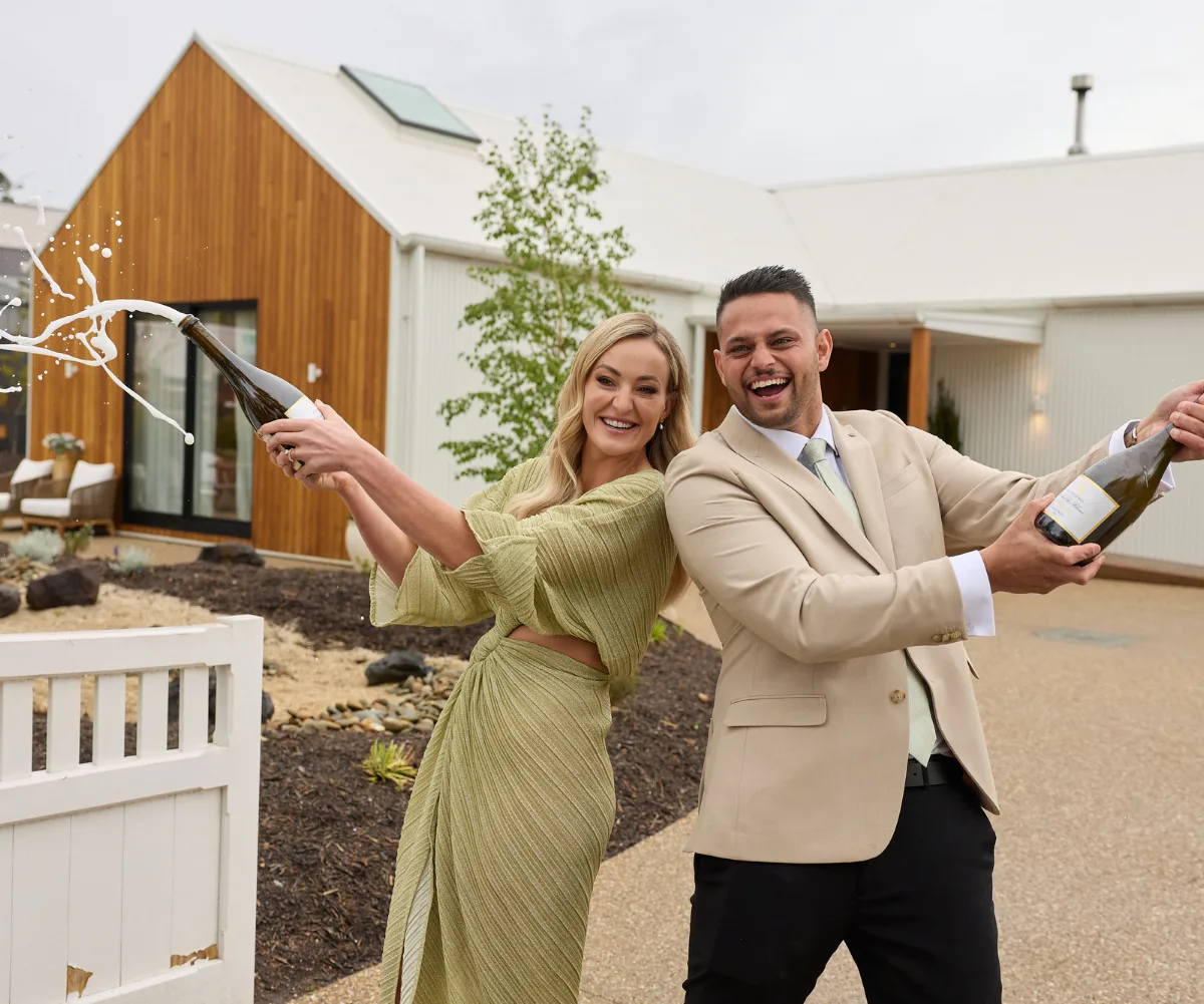 Britt and Taz shaking champagne out the front of House 3 on The Block 2025 after taking out the win.