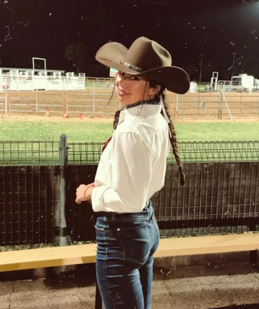 Madii Page poses in a cowboy hat at a rodeo.