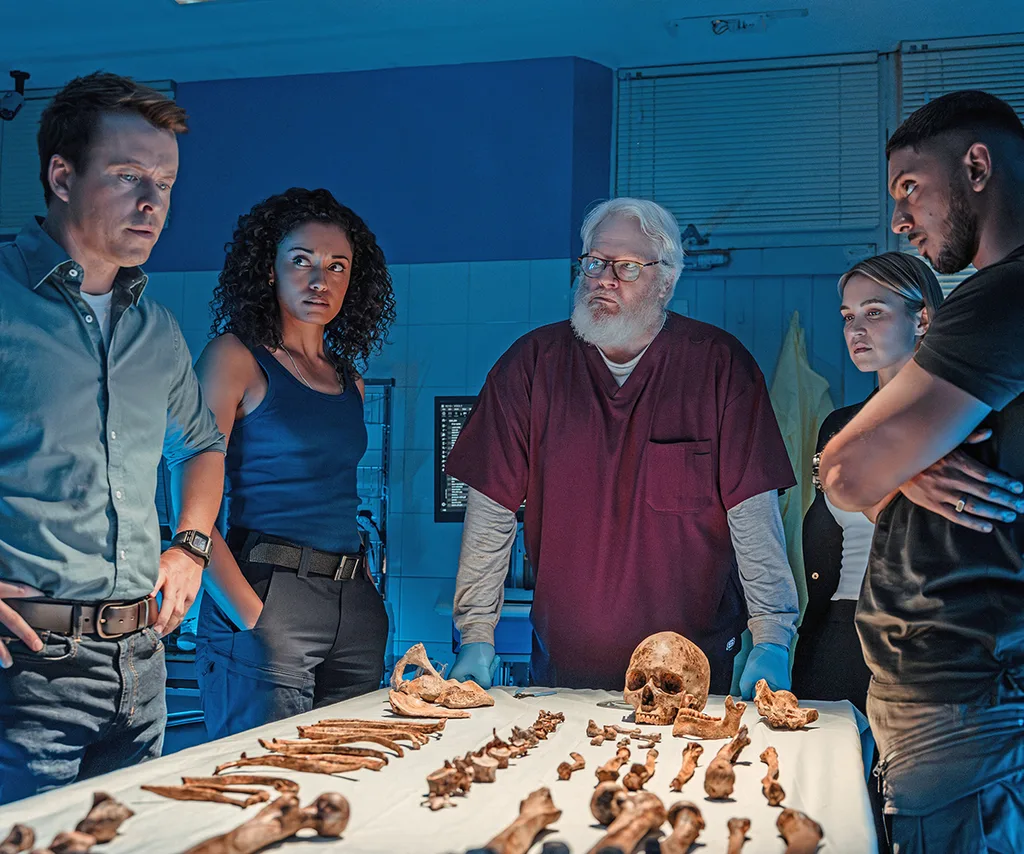 The NCIS: Sydney team looking over a table of bones.