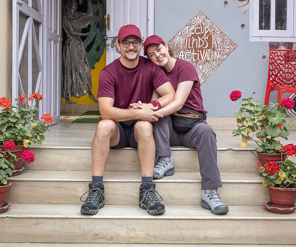 Rob Mills and Georgie Tunny hug each other on a set of stairs while filming for The Amazing Race: Celebrity Edition 2025.