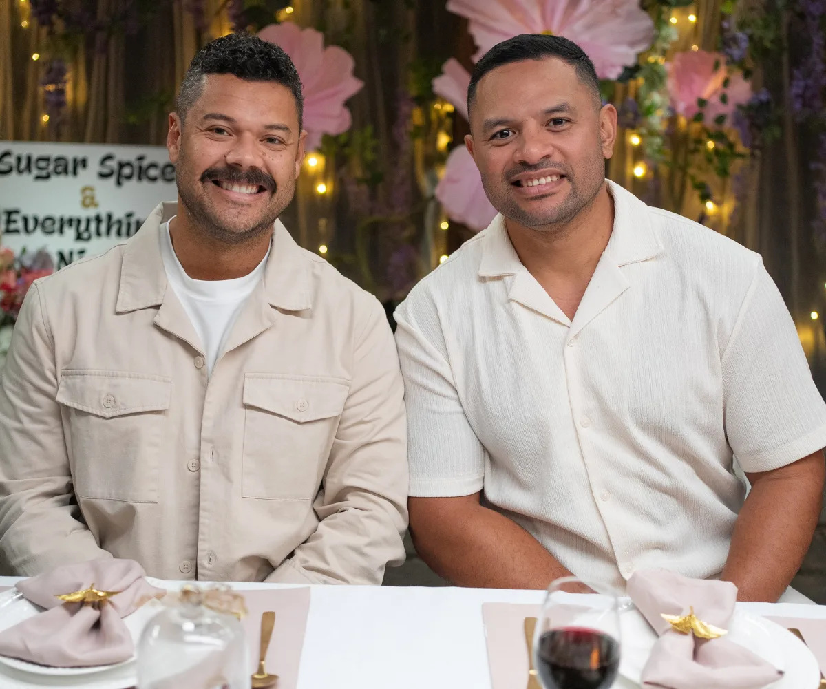 Justin and Will, smiling, sit next to each other at a table during My Kitchen Rules