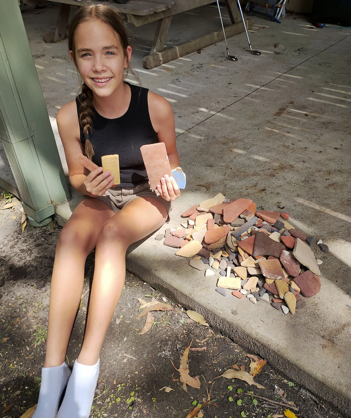 30 years worth of Walter Hood tiles collected from the beach at Wreck Bay, with my granddaughter Jasmine for human interest. (Image: Supplied)