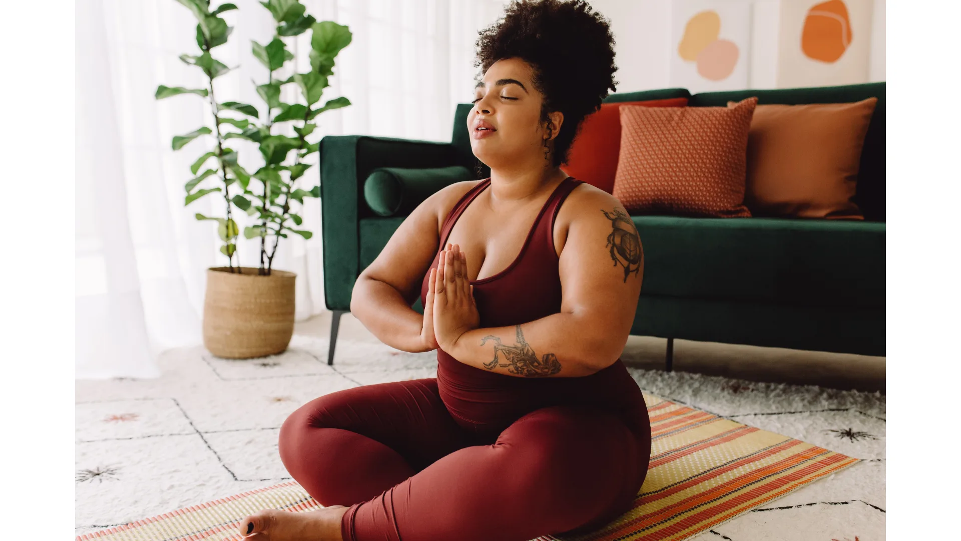 A woman in maroon exercise gear strikes a yoga pose.