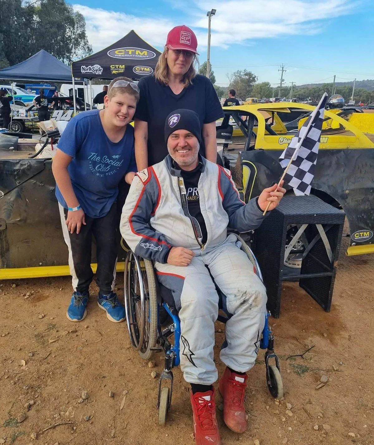 Chris holding the winners chequered flag and us, his pit crew, Jeremy and I. (Image: Supplied)