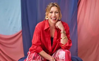 Claudia Karvan, in a red shirt, smiles at the camera